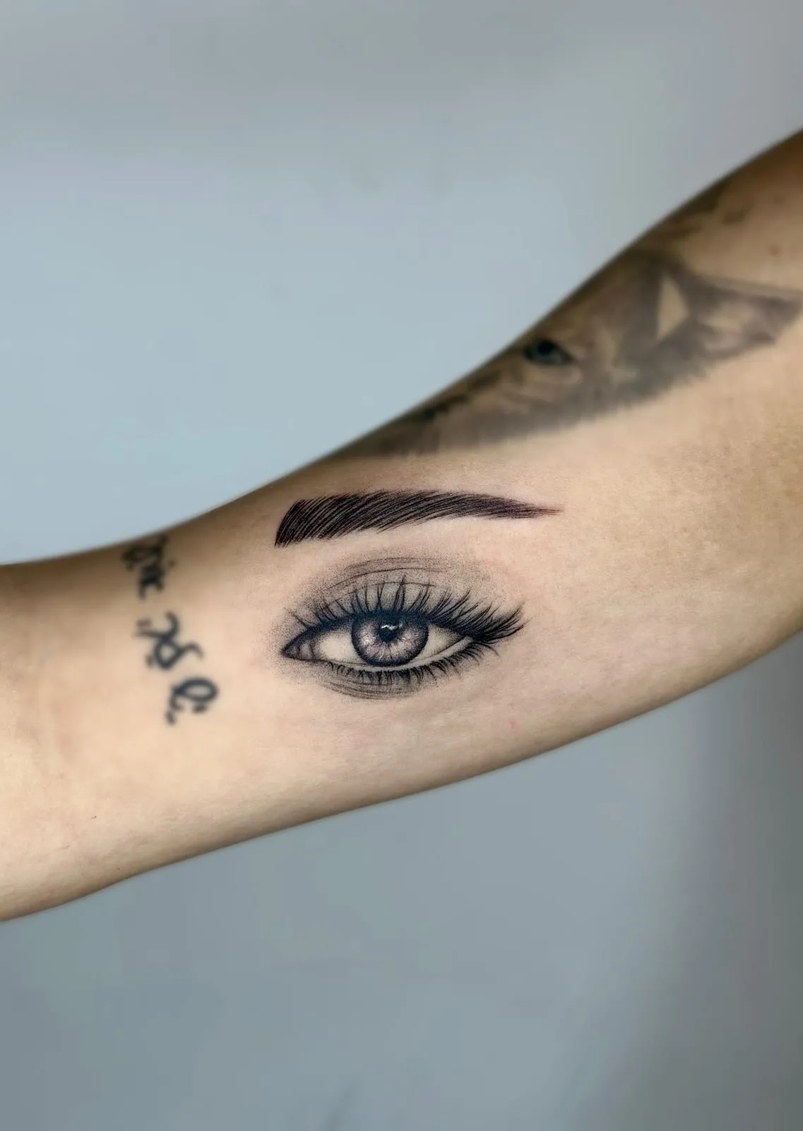 Realistic eye with a full brow and lashes, on the inner upper arm.