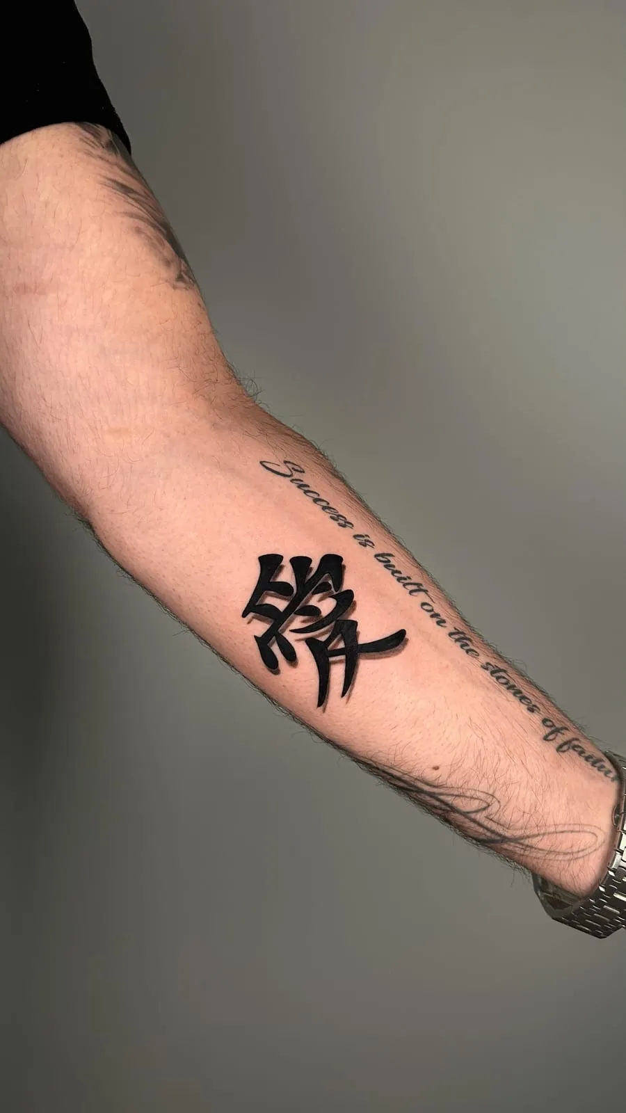 Bold brush-stroke kanji with script running along the forearm.